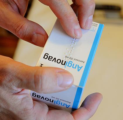 Una persona lee con los dedos la inscripción en braille de un medicamento