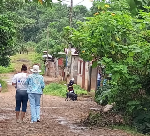 Dos mujeres de Nicaragua, una de ellas con bastón blanco, caminan por una calle con mucha vegetación